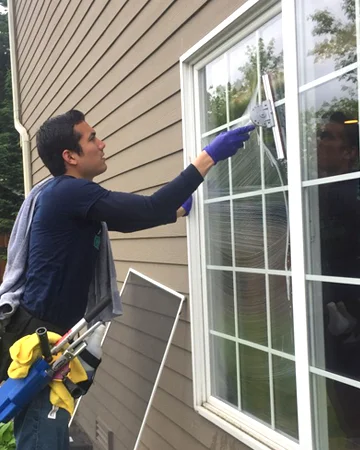Technician cleaning windows on a house