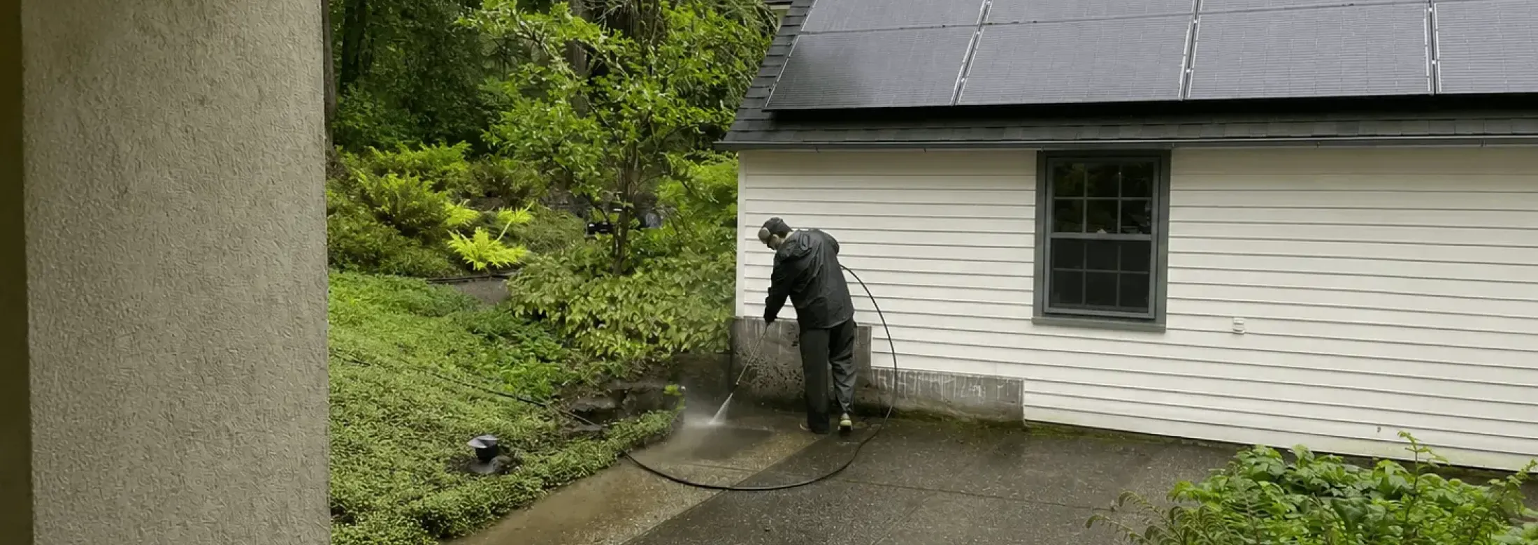 a technician pressure washing siding